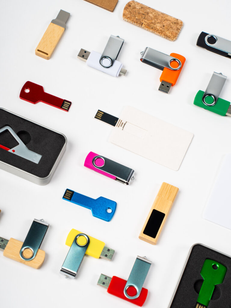 Memorias USB promocionales personalizadas con logo en distintos materiales: plástico, metal, madera, cuero y silicona. Capacidades desde 1GB hasta 128GB.